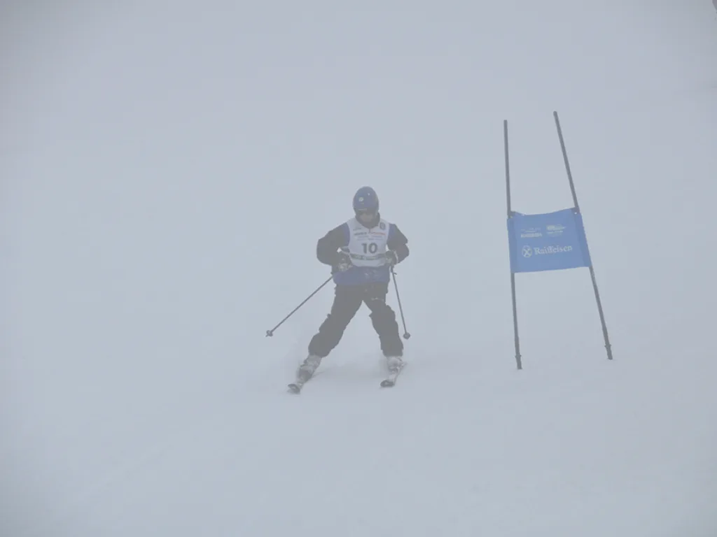 Skifahrer im Nebel neben dem blauen Tor.